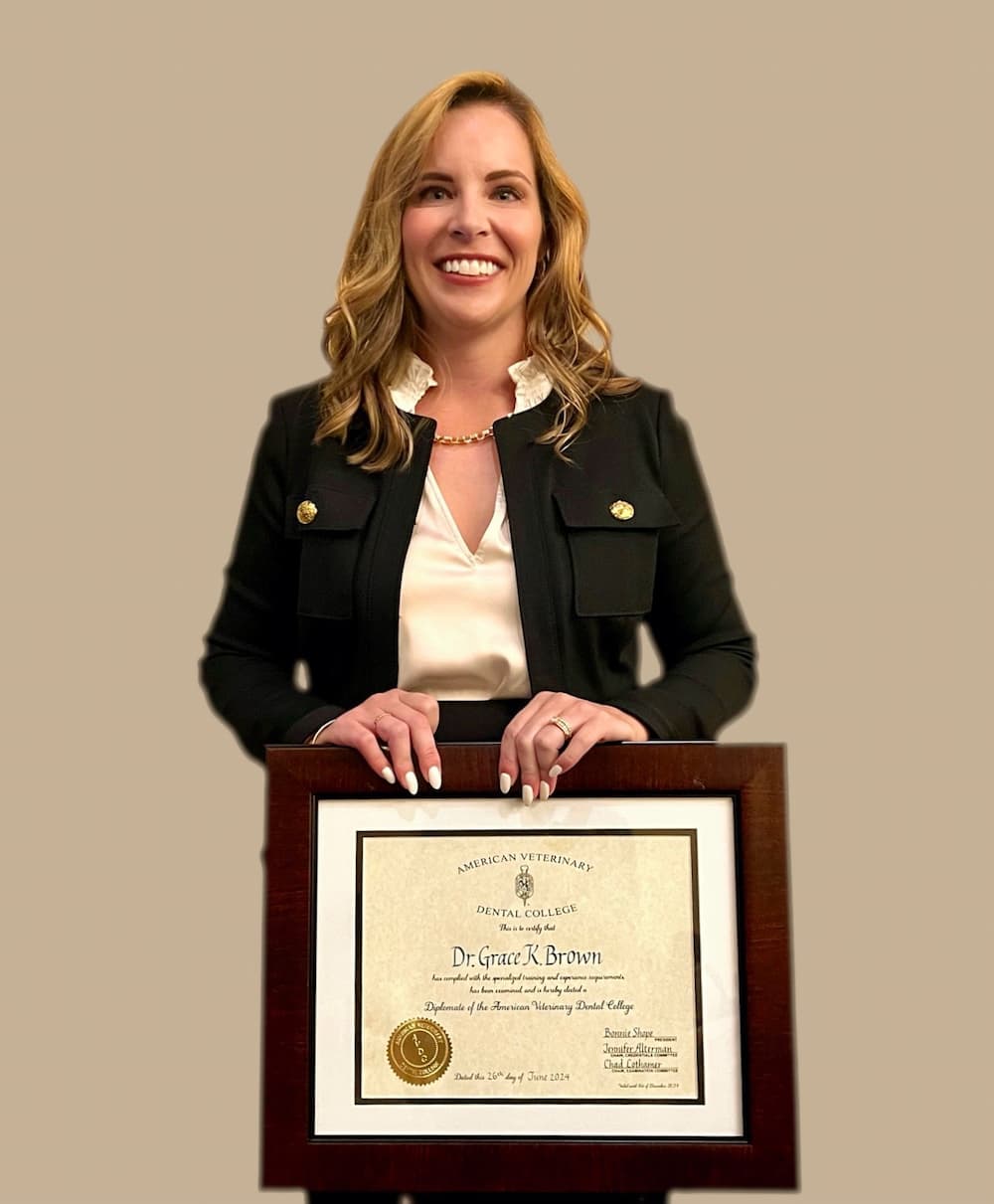 A person holding a framed certificate, wearing a black blazer and a white blouse, smiling against a plain background.